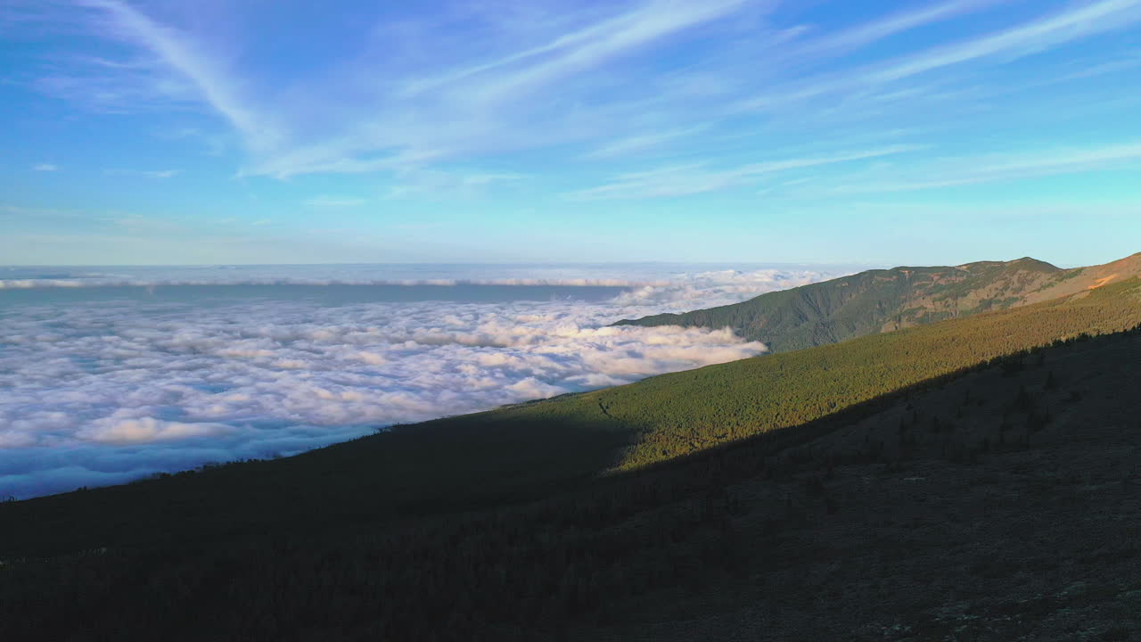 View from the Pico de Teide mountain on the coast of Gran Canaria covered in a dense cloud inversion in the evening with the Atlantic ocean on the horizon. Cloud inversion on a shore at sunset 4K.