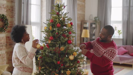 black family couple decorating christmas tree at home