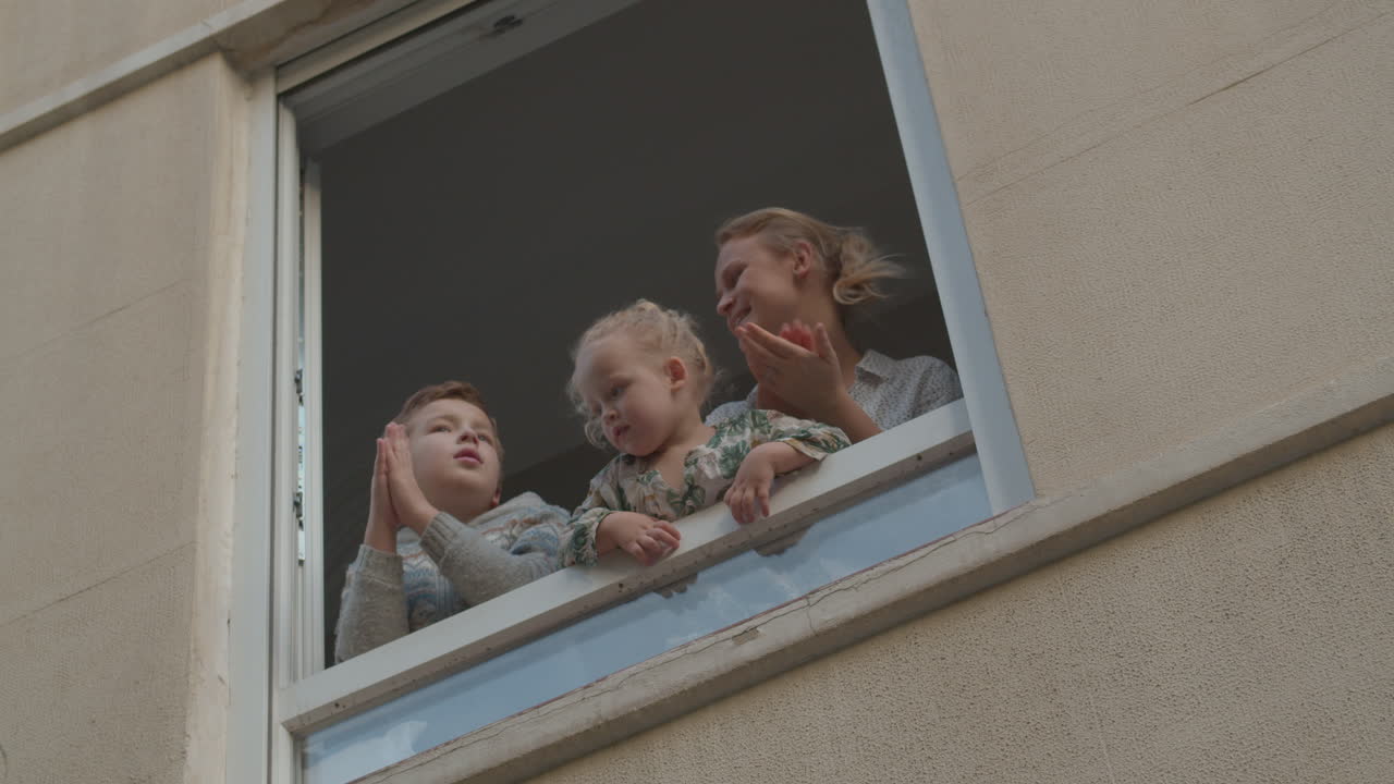 Family in open window during Covid-19 quarantine