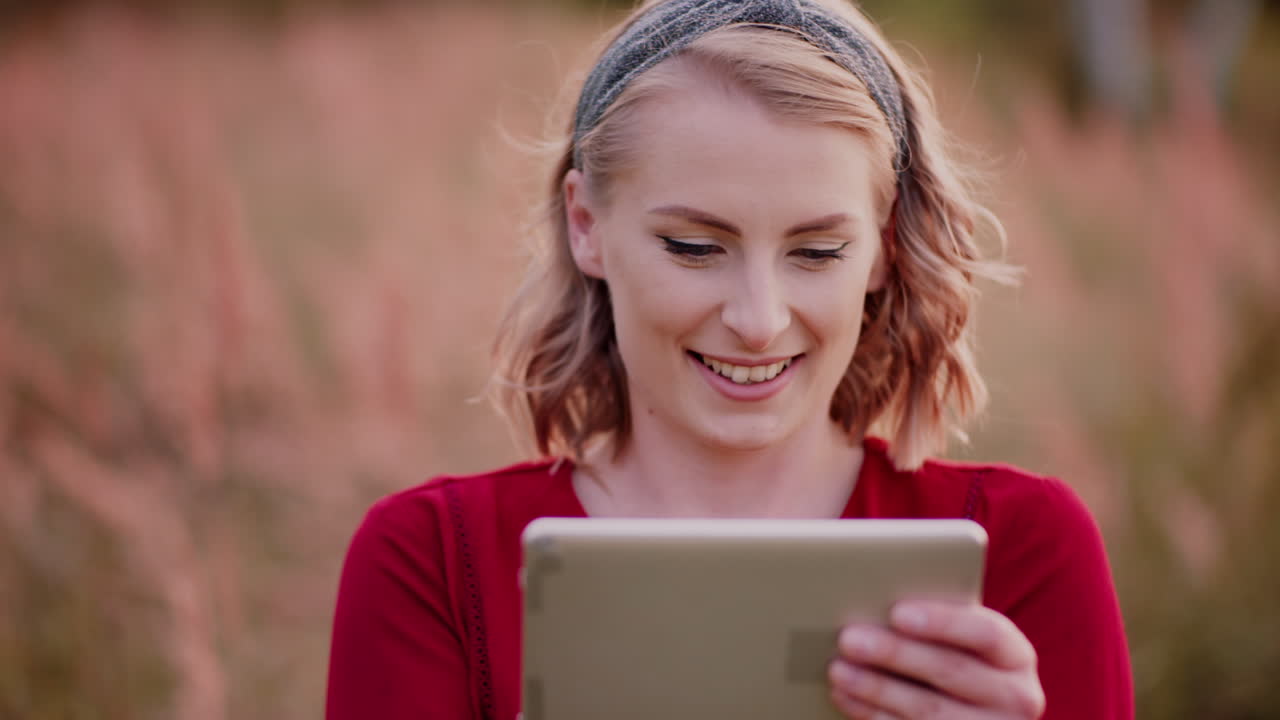 joven mujer sonriente escribiendo en una tableta digital al aire libre 3