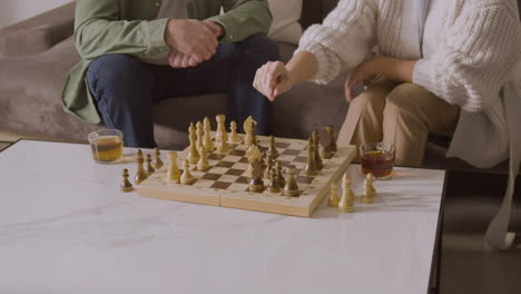 Close-Up-Of-Two-Unrecognizable-People-Playing-Chess-While-Sitting-On-Sofa-At-Home