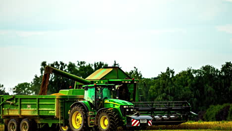 combine harvester tractor with trailer harvesting crops on agricultural land