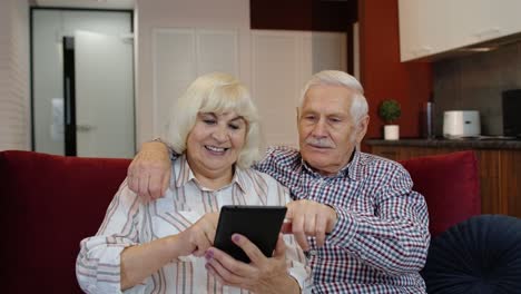 Senior-old-couple-grandparents-talking-and-using-digital-tablet-computer-at-home.-Internet-shopping