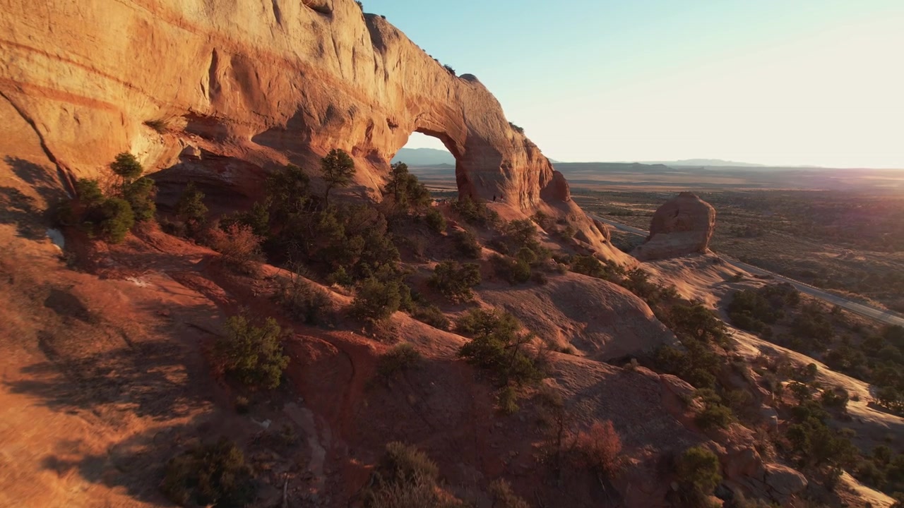 Veduta aerea di un arco naturale lungo la strada nel deserto dello Utah al tramonto, ripresa con drone.