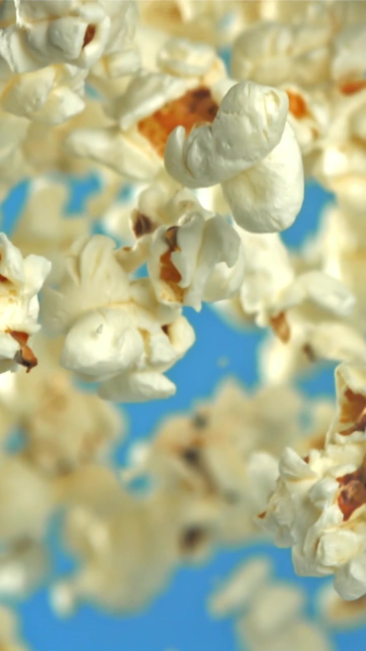 Popcorn che fluttuano verso l'alto su sfondo blu al rallentatore.
