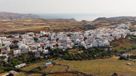 aerial: revealing kythnos chora at sunrise, with golden morning light gently illuminating whitewashed homes and quiet cycladic streets