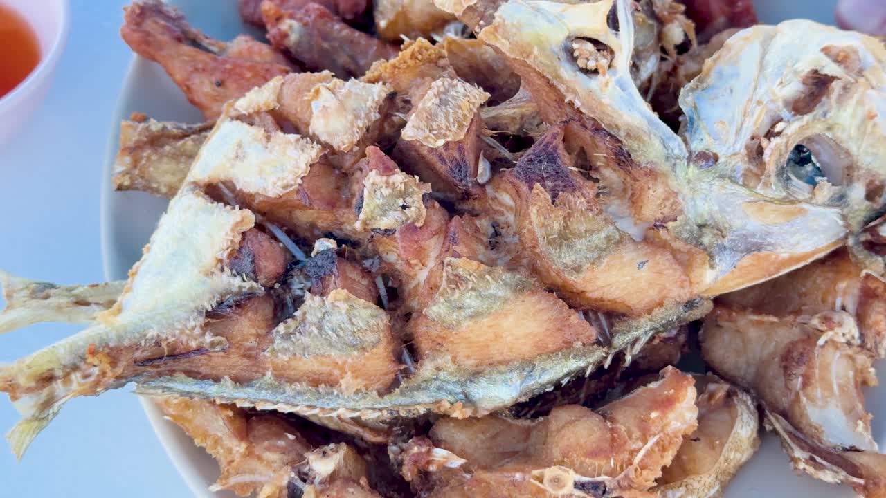 Close-up of a freshly cooked fish dish on a boat in Phuket, Thailand. Bright lighting highlights the crispy texture and vibrant colors