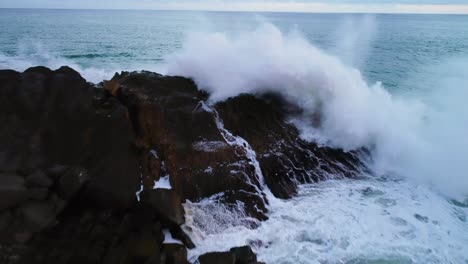 drone pullback on wave crashing on rocks