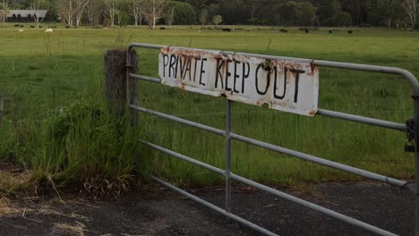 a weathered gate with a warning sign in a field