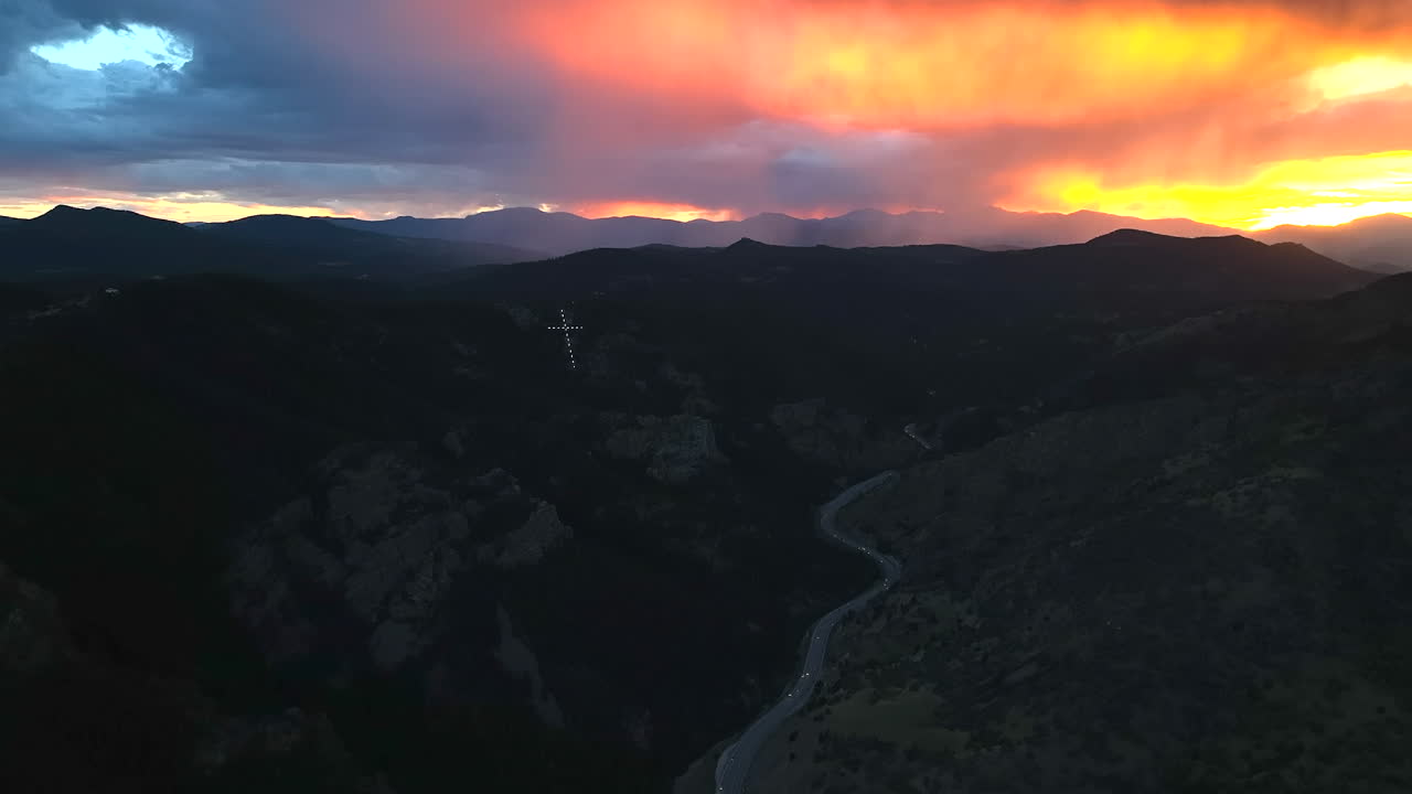 increíble atardecer con jesus cristo cruz en la cima de la montaña avión no tripulado cinematográfico monte lindo colorado nubes de lluvia naranja amarillo rosa verano cristiano increíble la cruz más grande de estados unidos morrison hacia adelante