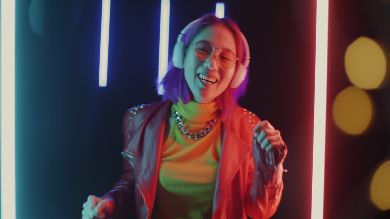 Young Woman Dancing to Music with Neon Lights