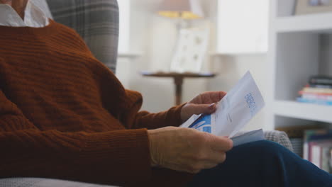 worried senior woman at home looking at energy bill during cost of living energy crisis