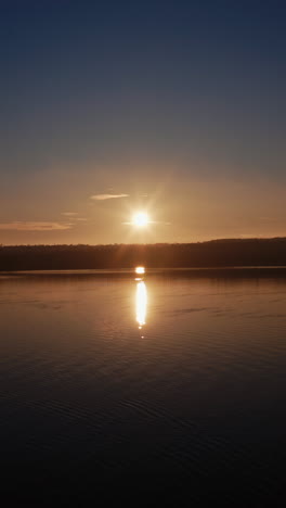 river at sunset. setting sun reflects on the water surface in the evening. beautiful view of the lake with setting sun on the evening sky. vertical video