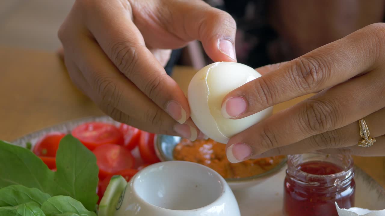 mujer pelando un huevo cocido en el desayuno