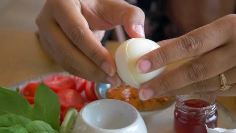 woman peeling a boiled egg at breakfast