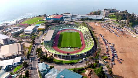 aerial of a soccer league game being played in santiago wanderers stadium in valparaíso, sea in background, chile