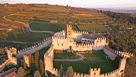 Vista-Aérea-Del-Castillo-Scaligero-De-Soave-Con-Campos-Y-Viñedos-Al-Fondo-Durante-La-Puesta-De-Sol-En-Verona,-Italia