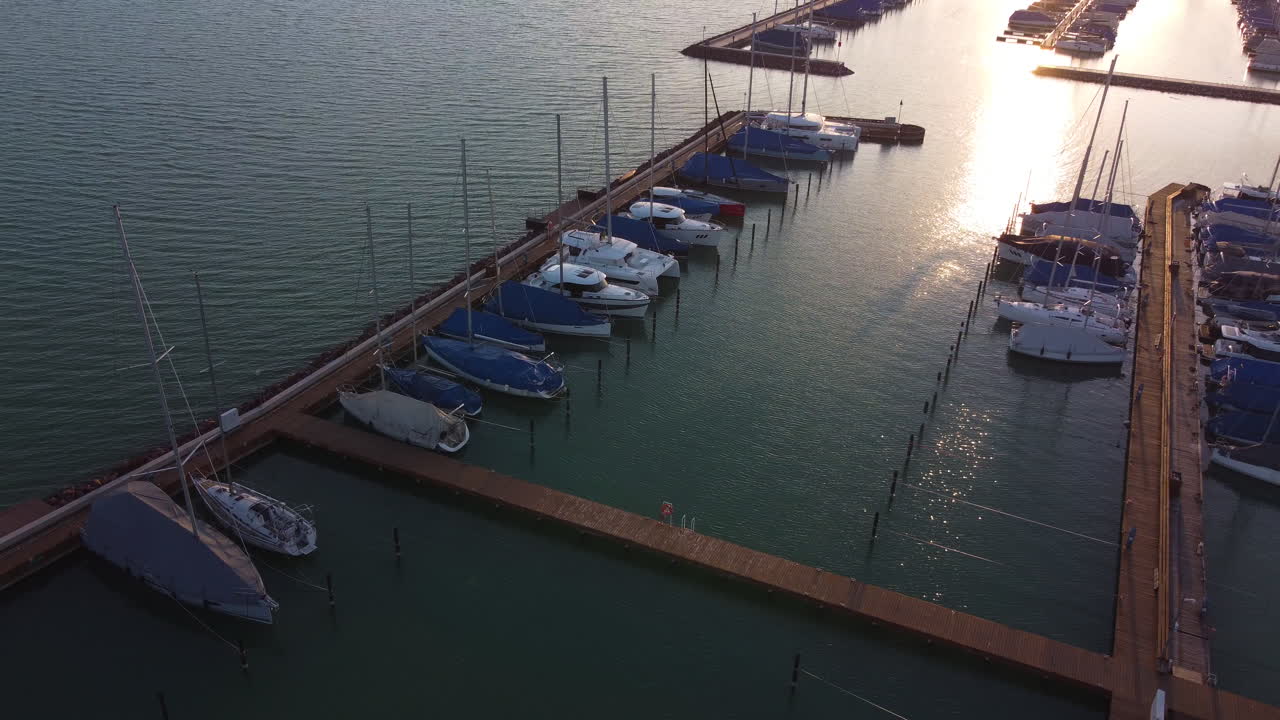 Sunset over Balatonfured marina with piers casting long shadows across calm water surface