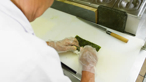 chef masculino preparando un rollo de arroz en la cocina 4k