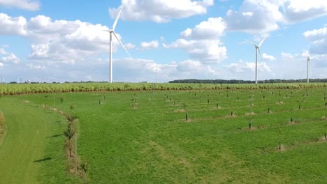 drone rises over a grass field filled with wind turbines on a fluffy cloud day