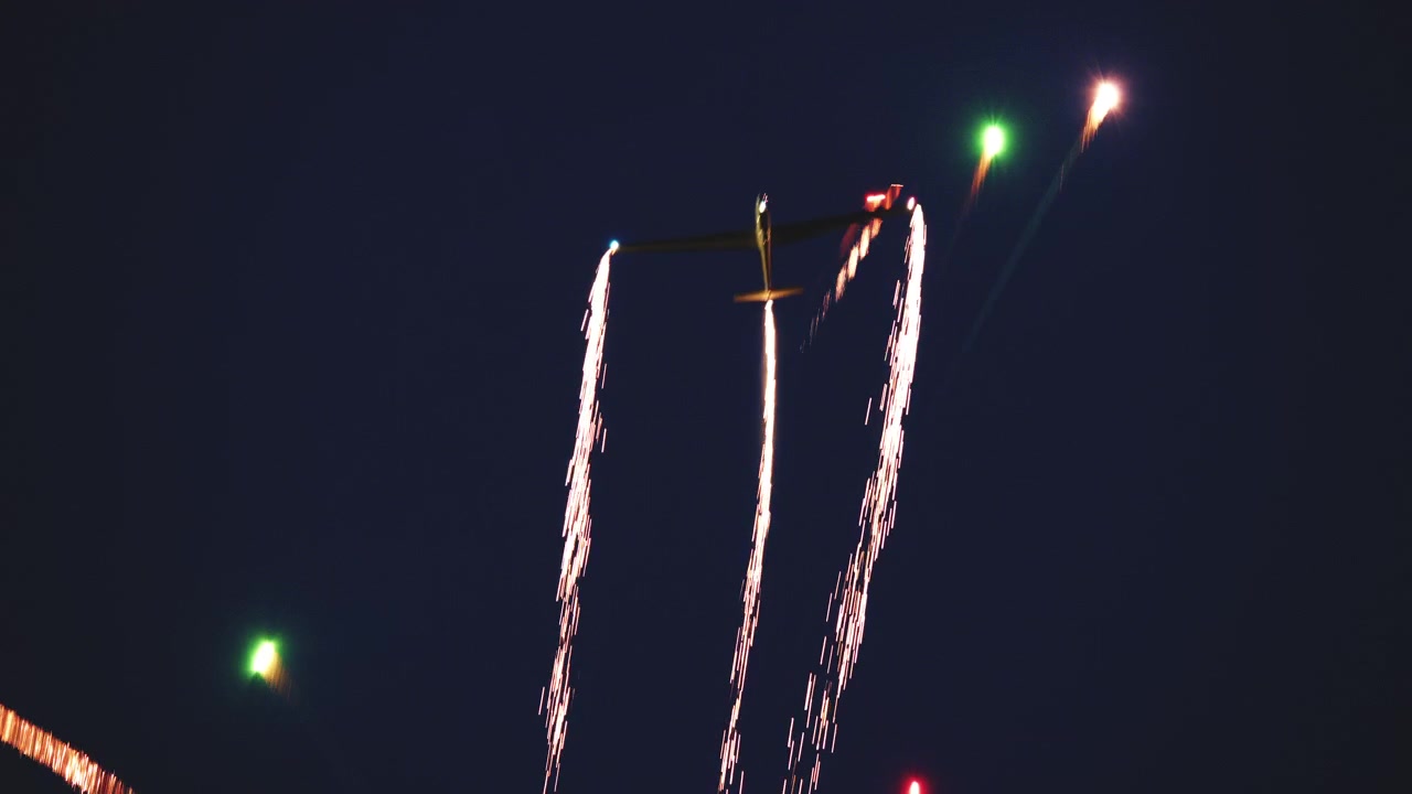 Un aliante esegue acrobazie aeree di notte, lasciando una scia di scintille.
