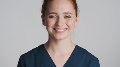 redheaded nurse in front of camera on gray background.