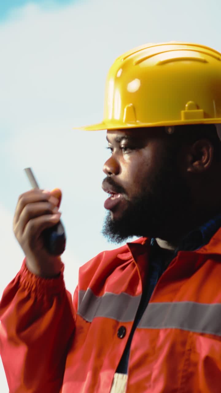 Vertical video Offshore platform worker speaking in walkie talkie, scheduling equipment repairs