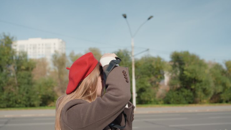 Redhatted woman taking pictures at urban church. Woman with red beret snaps images of quiet city chapel scene. Woman wearing red beret photographs vintage brick chapel in peaceful city square