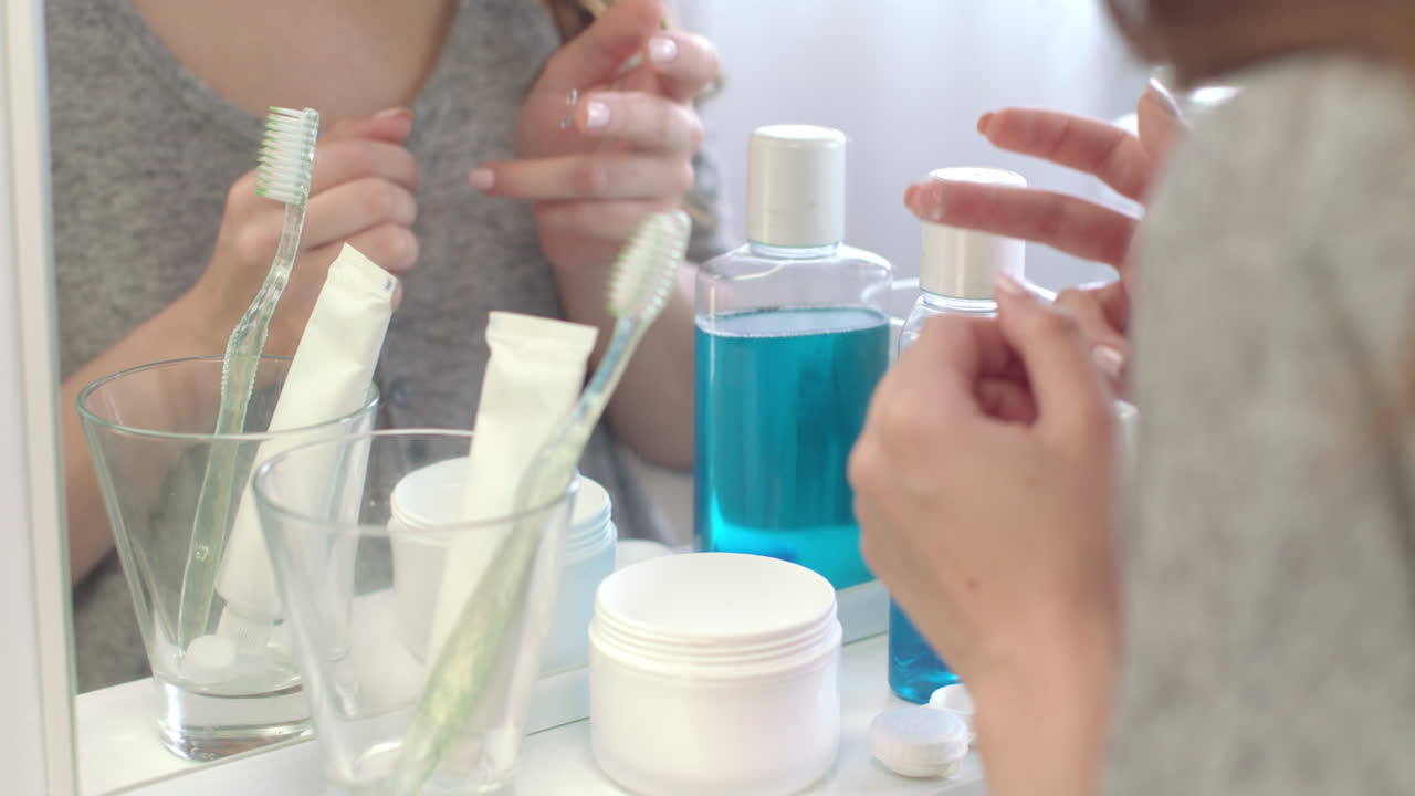 가정 화장실 에서 앞 거울 을 사용 하기 위해 눈 렌즈 를 들고 있는 여성 의 손