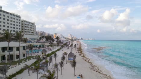 Aerial-View-of-a-beautiful-beach-with-waves-and-palm-trees-in-Cancun-Mexico,-Panning-Shot