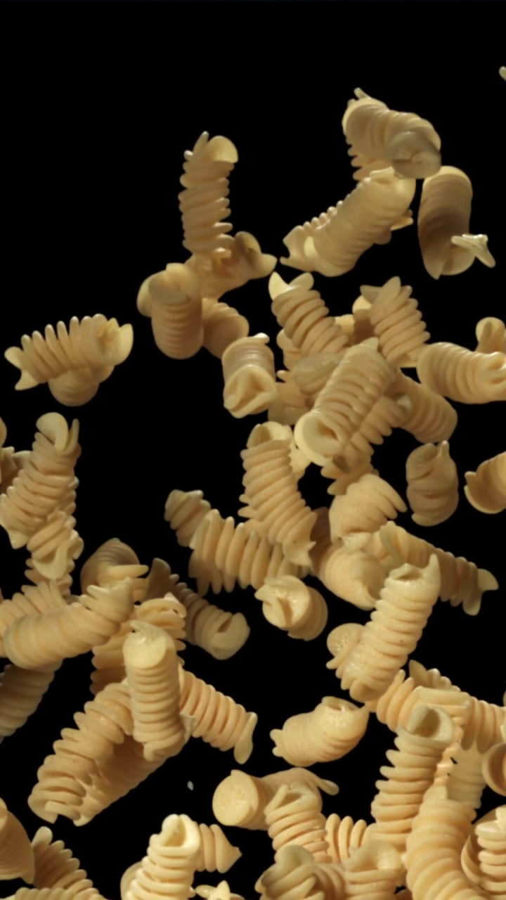 Fusilli secchi che cadono al rallentatore su sfondo nero