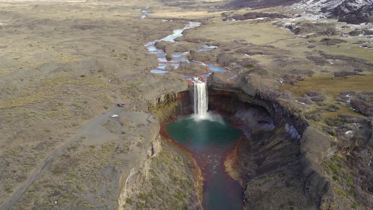 Aerial orbit around the Salto del Agrio waterfall flowing into rocky canyon environment, Neuquén, Argentina