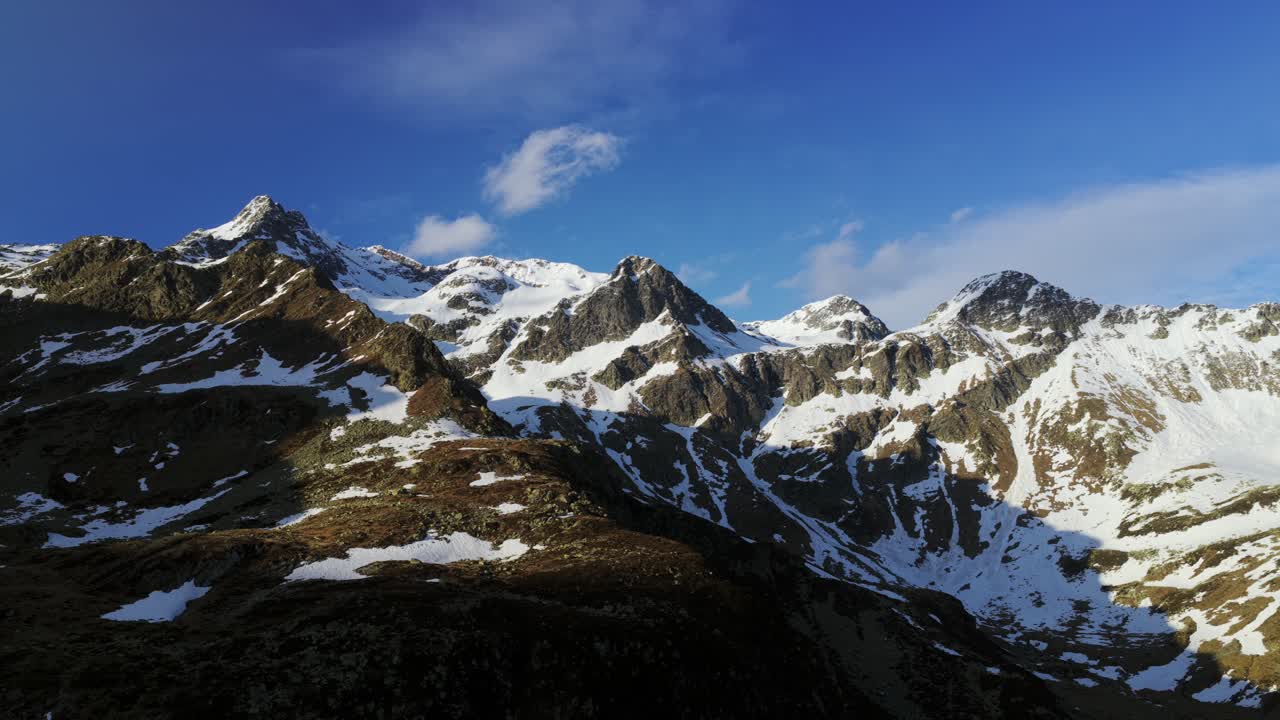 Majestic snow-capped Montespluga mountain range in Italian Alps. Aerial drone lateral view