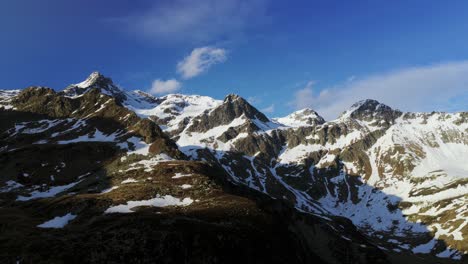 majestic snow-capped montespluga mountain range in italian alps. aerial drone lateral view