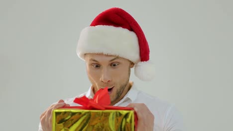 excited man in santa hat opening a christmas gift