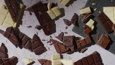 person picking up piece from broken bars of milk plain and white chocolate