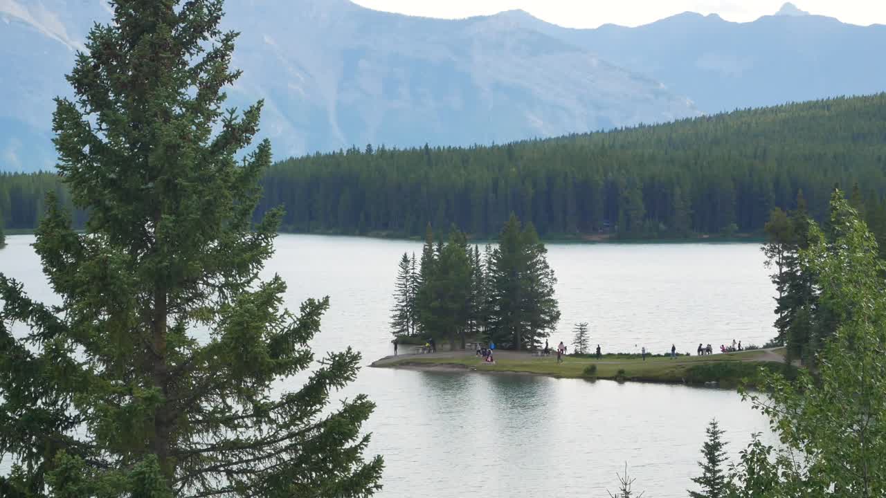 Splendida vista naturale del lago Two Jack con una bellissima foresta di pini e le montagne rocciose sullo sfondo, nel Parco Nazionale di Banff, Alberta, Canada, in una giornata di sole estiva