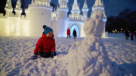 child building snowman near an ice castle