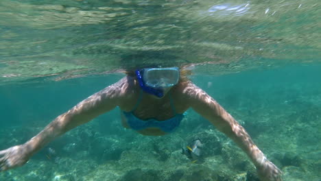 woman in snorkel diving and waving with hands