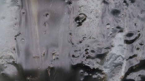 wide shot of a dark viscous liquid slowly moving