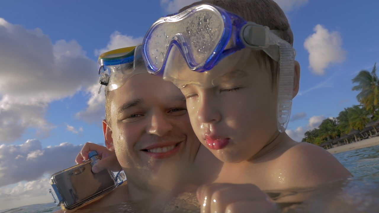 vista en cámara lenta de un joven padre feliz con su hijo en el agua con máscaras de buceo isla de port louis mauricio