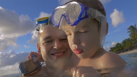 Vista-En-Cámara-Lenta-De-Un-Joven-Padre-Feliz-Con-Su-Hijo-En-El-Agua-Con-Máscaras-De-Snorkel-En-La-Isla-De-Port-Louis-Mauricio