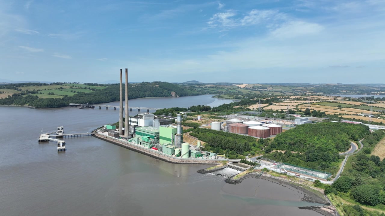 Prospettiva aerea di una grande centrale elettrica accanto al fiume Suir in Irlanda, con infrastrutture energetiche su uno sfondo naturale lungo il fiume