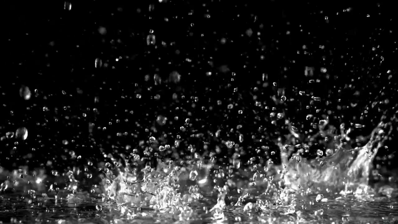 黒い背景に落ちて水しぶきを上げる雨粒