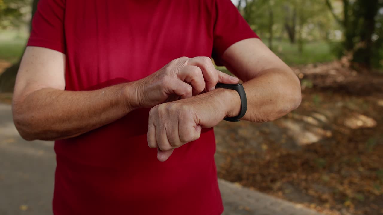 Anziano corridore che inizia a toccare il touchscreen su uno smartwatch, monitorando la distanza e controllando il battito cardiaco.
