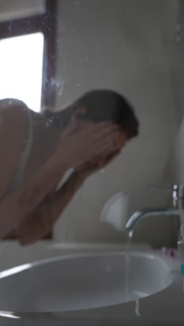 woman washing face in bathroom