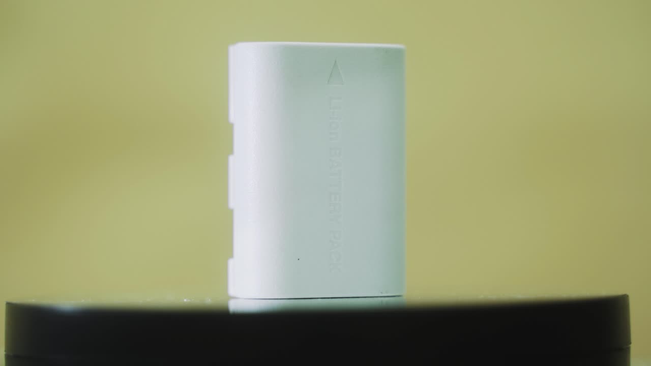 un primer plano giratorio de una batería de cámara de litio blanca permanente, cámara lenta 4k