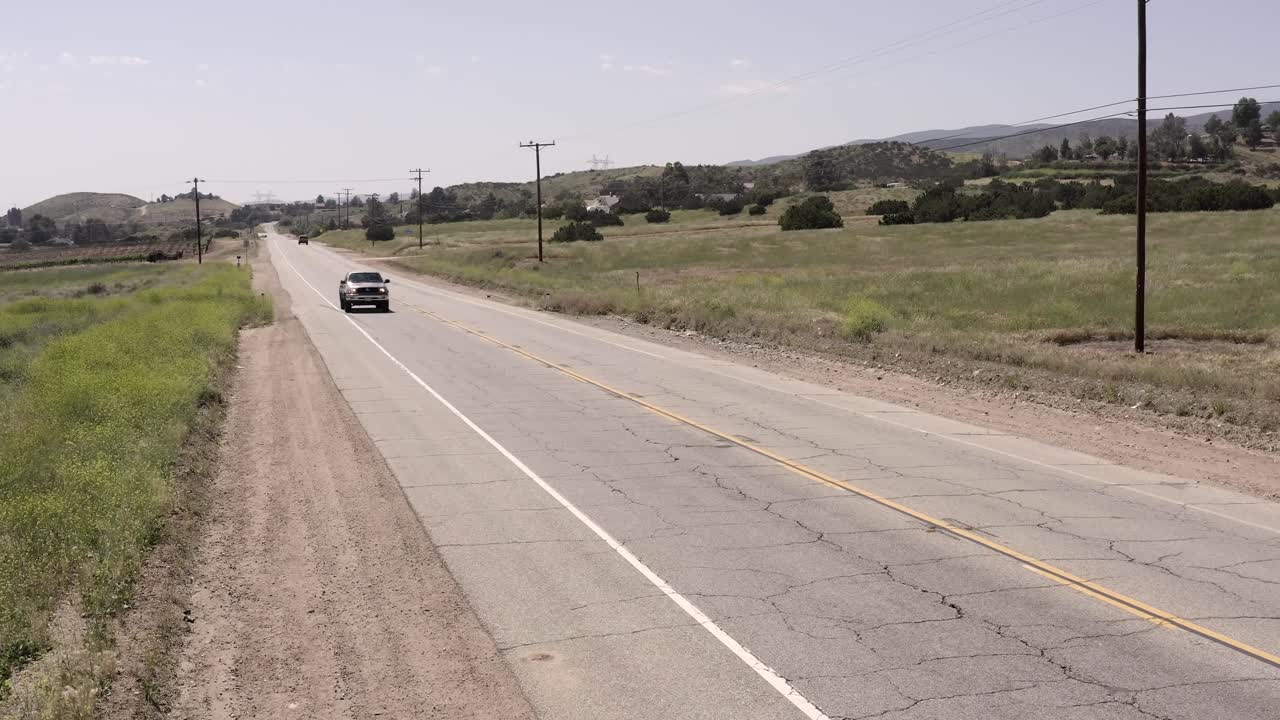 Pick-up truck driving along American country road, aerial remote rural setting
