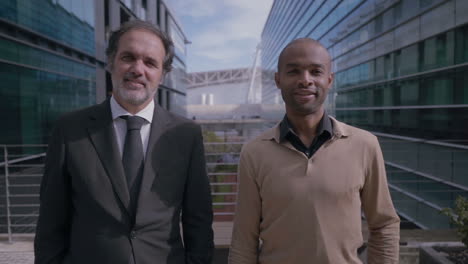 successful multicultural businessmen posing near office building