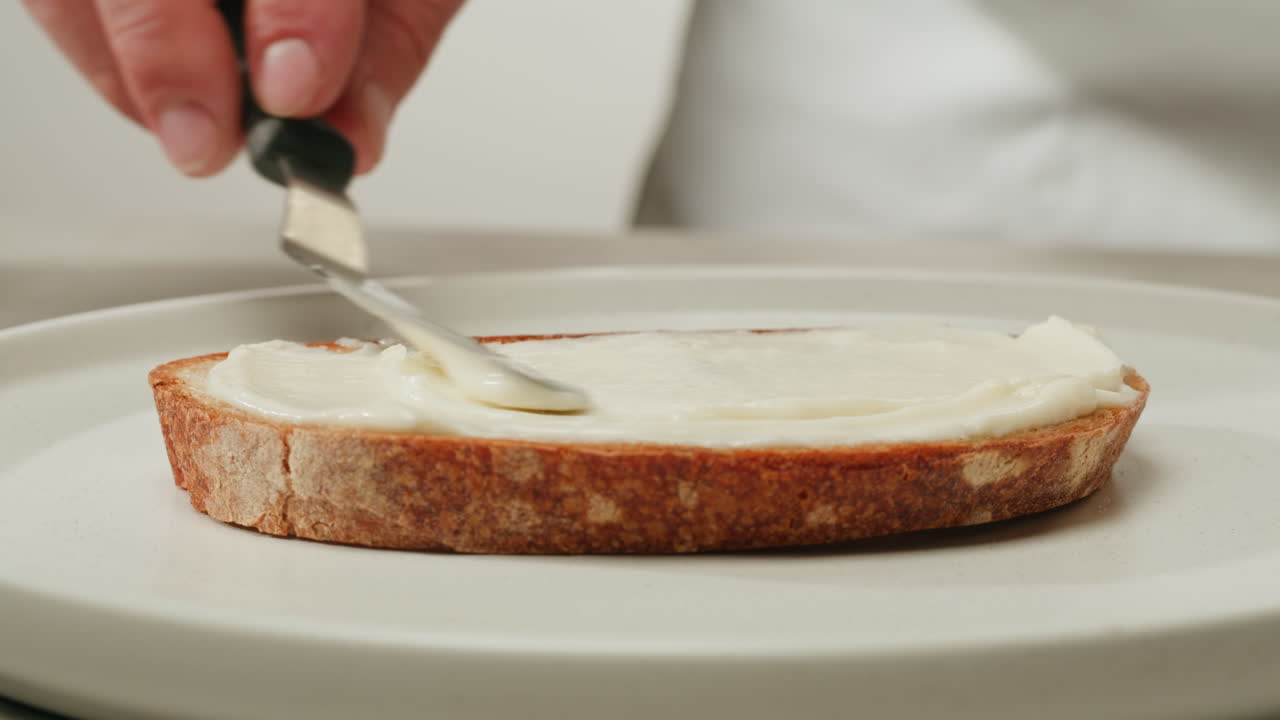 Spreading cream cheese on a slice of bread
